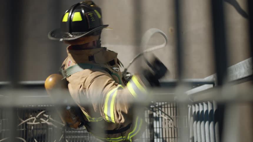 A firefighter pulls a rope up over a railing