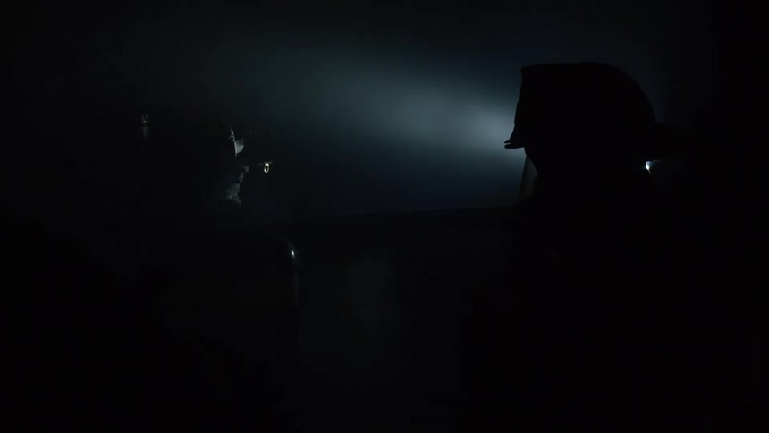 Two firefighters stand in the dark in the smoky area