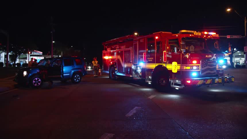 Fire truck with lights flashing next to parked car at night