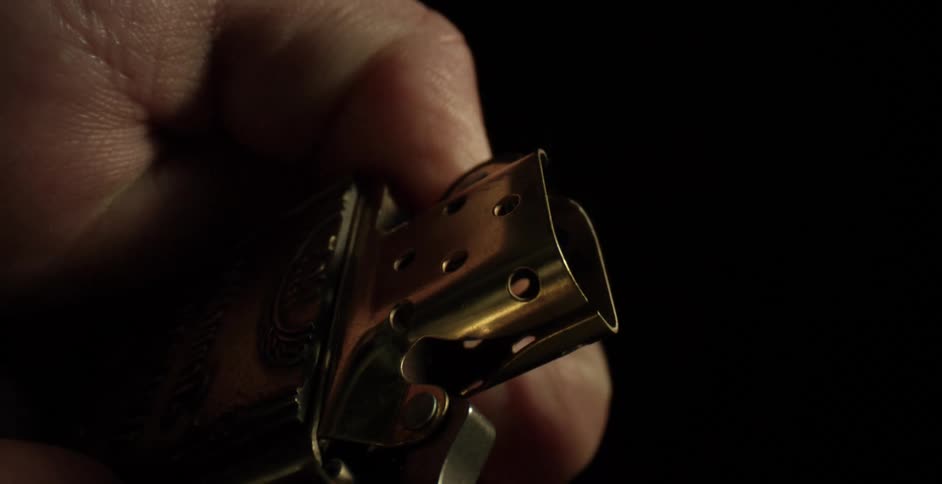 A man opens a gold lighter and flicks it on