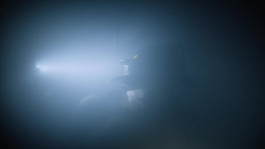 Two firefighters search a smoke filled area