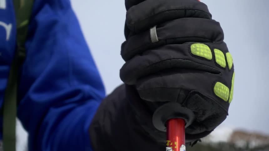 A skier tightly grips a ski pole while standing near a mountain