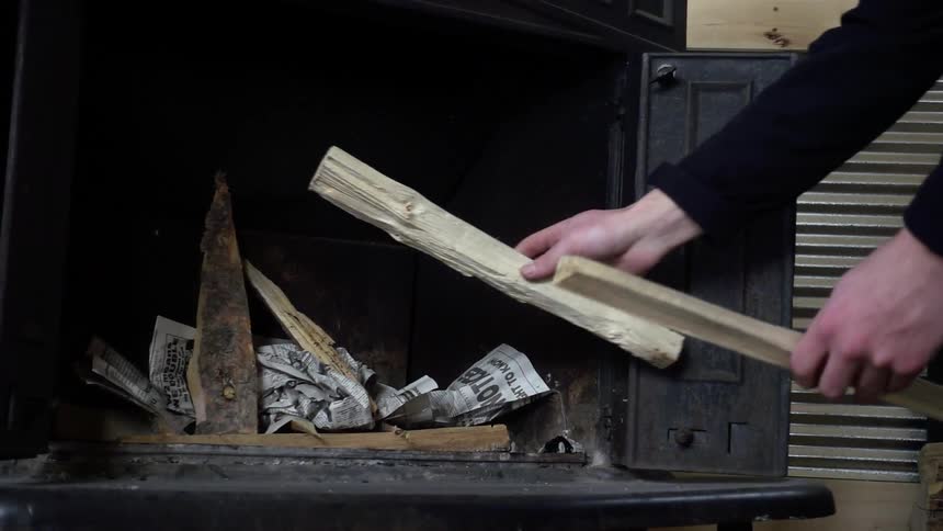 A man puts firewood in a fireplace