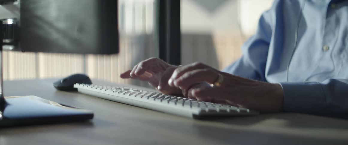 Man sitting at the table types on a computer and makes a phone call in a room