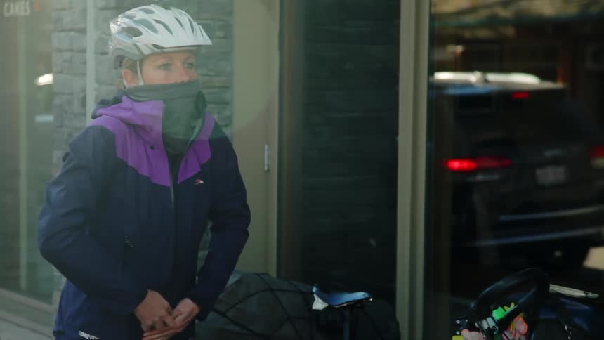 A woman puts on her bike helmet as she prepares to get on her bike