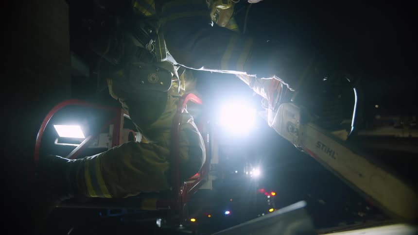 Firefighter uses a chainsaw to cut a hole