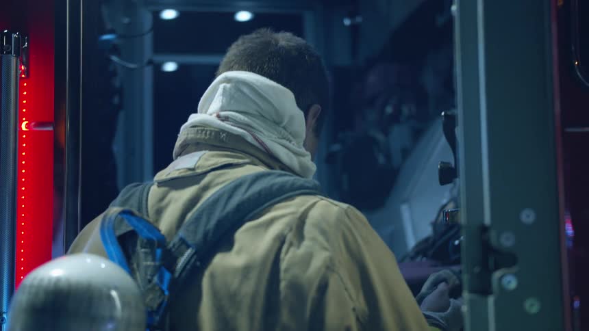 A male firefighter reaches inside the fire truck door