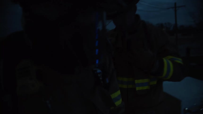 A firefighter hauls himself up to the top of the ladder truck