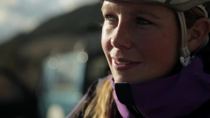 A woman with a helmet on stands outside smiling