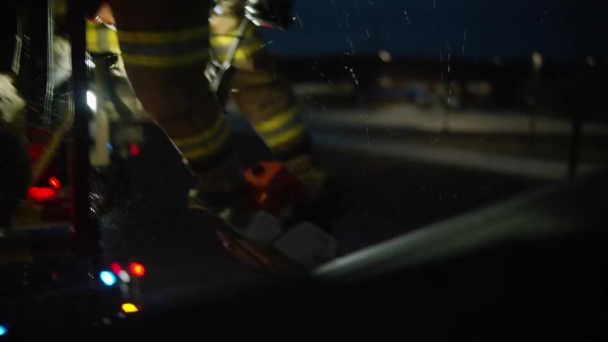 A firefighter stands on a platform using a chainsaw to cut a hole in a roof