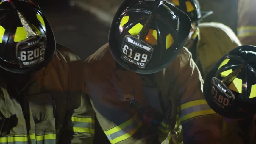 A group of firefighters work closely on the ground doing something
