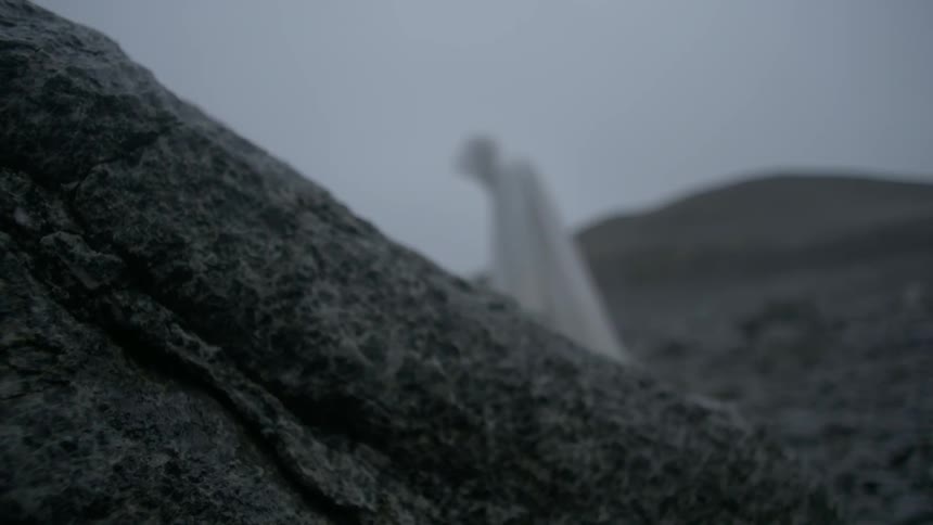 A cloaked figure stands alone outside