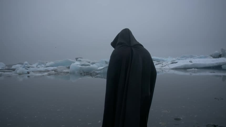A cloaked figure stands in front of an icy lake