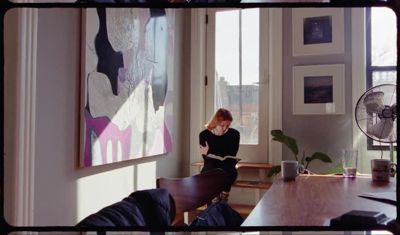 Red haired woman reads a book in the living room at home