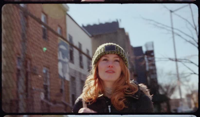 Red haired woman walks down the street and smiles slightly