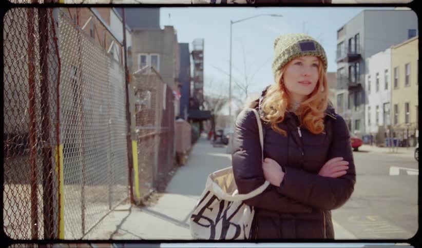 Red haired woman walks on the pavement in the neighborhood