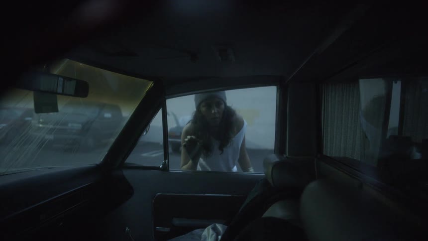 A young woman peers in to the inside of a vehicle