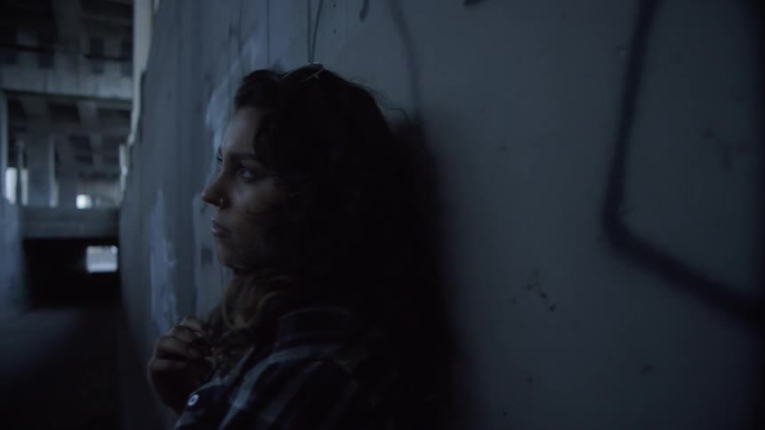 A woman is leaning against the concrete wall