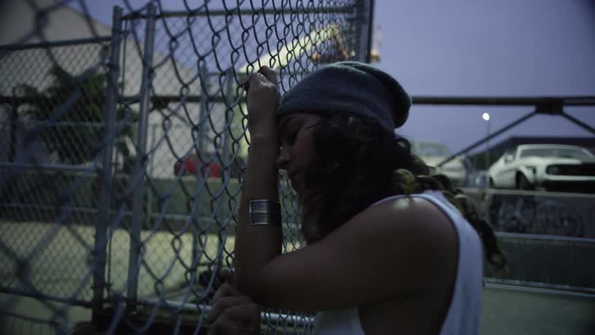 A woman is leaning on the fence