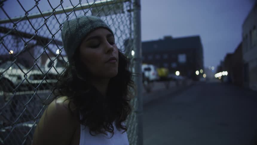 Woman wearing beanie reclines on wired on city street at sunset