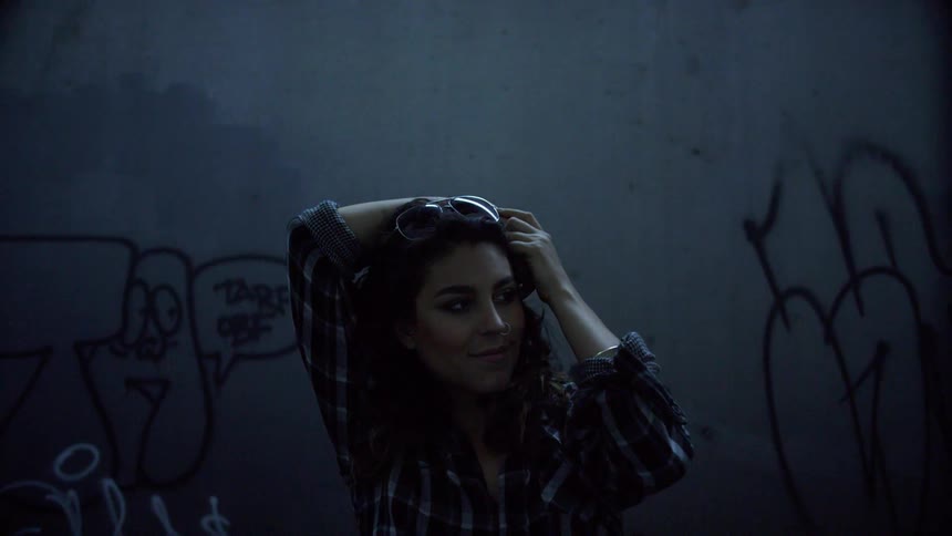 A woman stands in front of a wall with graffiti