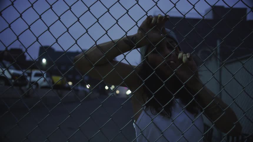 A female teenager seductively hangs on to a fence