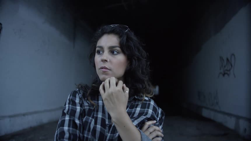 Woman fidgets as she stands in a tunnel with her glasses up on her head