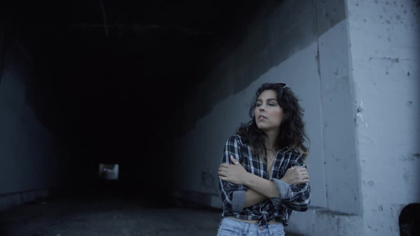 A woman rubs her arms as she stands at the entrance of a tunnel