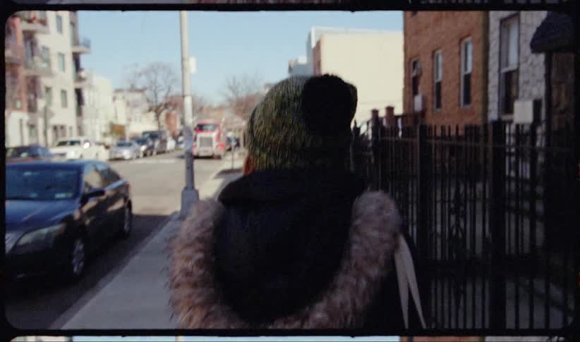 A woman in winter clothing walking down a city sidewalk during the day