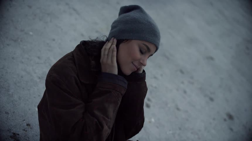 A teenager sits on concrete and moves like she is dancing