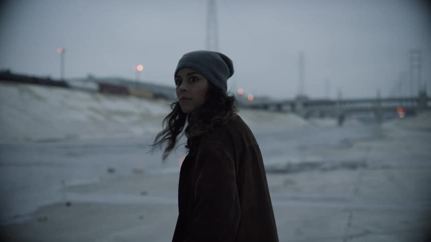 A teenager walks along an empty street and looks behind her