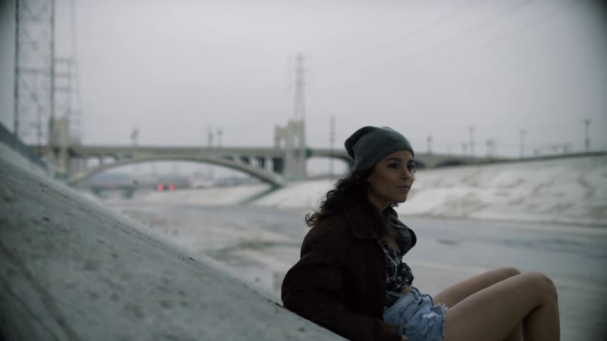 A teenager lies on a cement embankment and then sits up