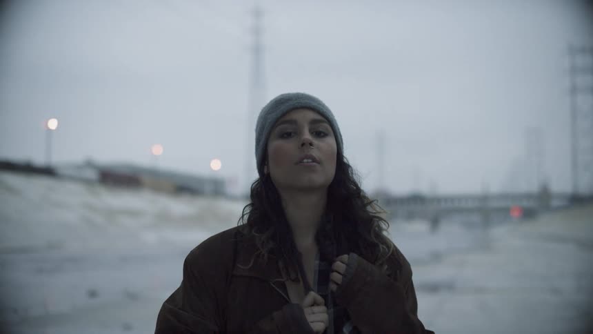 Brunette woman wearing a beanie and coat poses for the camera outdoors