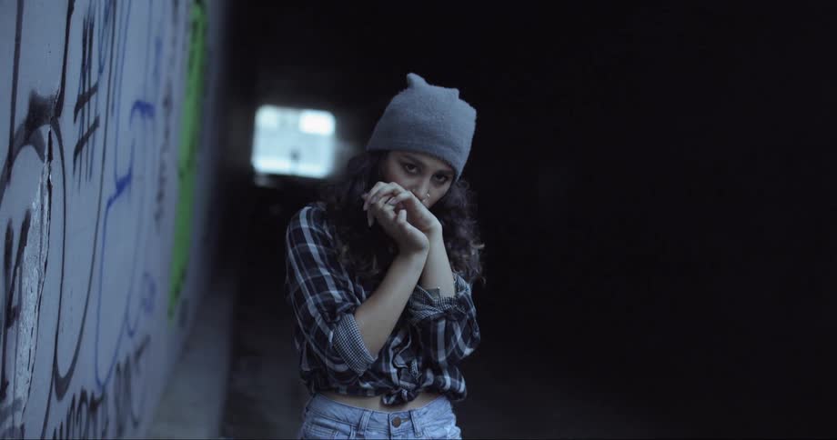Woman wearing a toque with her hands clasped together moves forward in a tunnel