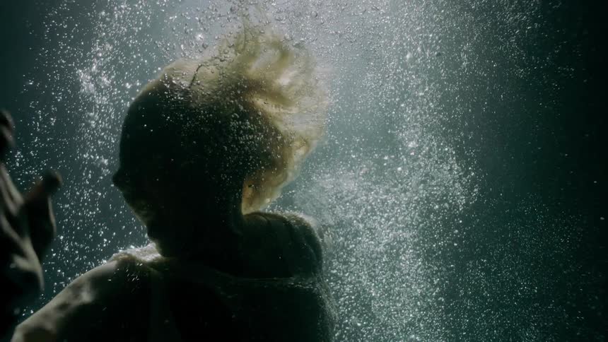 Woman wearing dress screams underwater