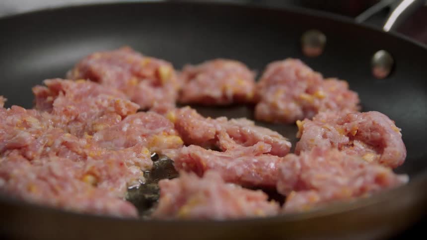 A person cooks meat in a pan at home