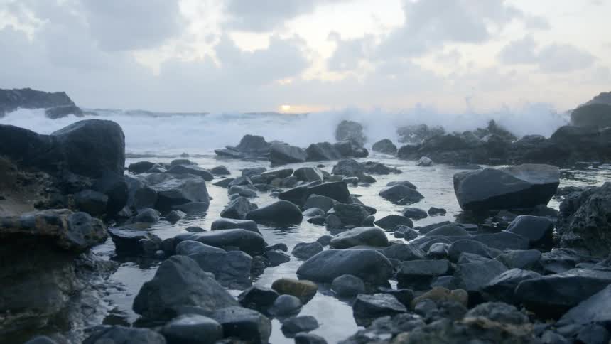 Ocean waves crash against the rocks at sunset