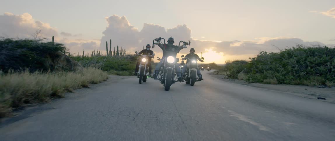 A group of people drive motorcycles
