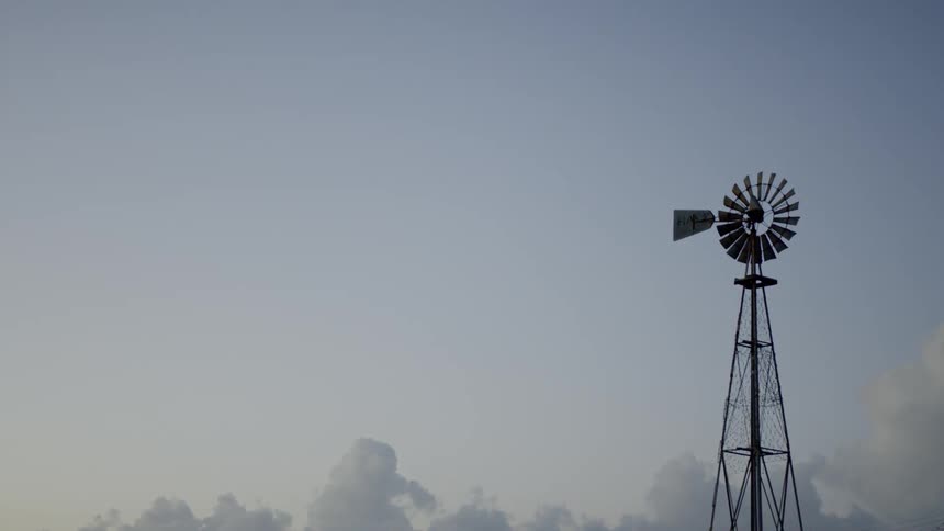 A windmill on a tower turns slowly