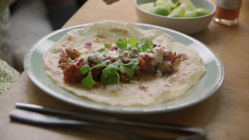 Woman pour lemon juice on the filling inside a flour tortilla