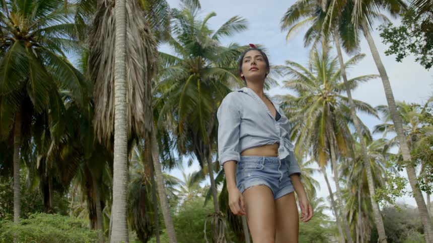A young woman turns around and looks at the tropical area around her