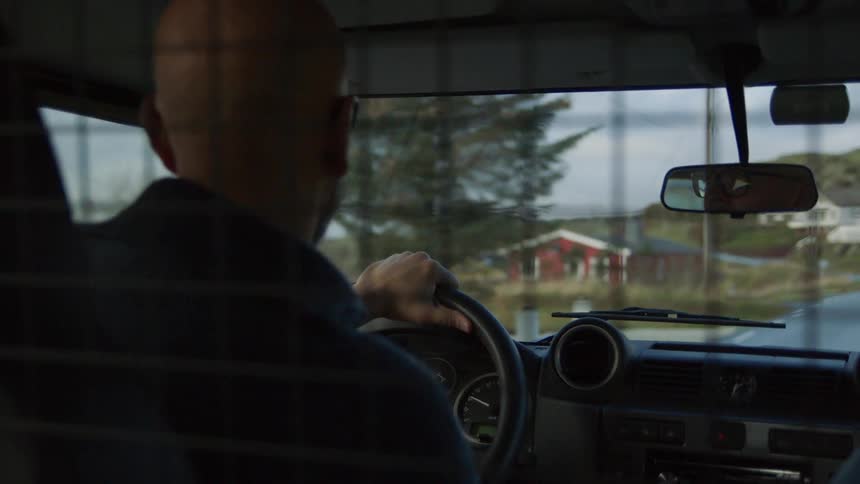 A man drives a car through a rural countryside