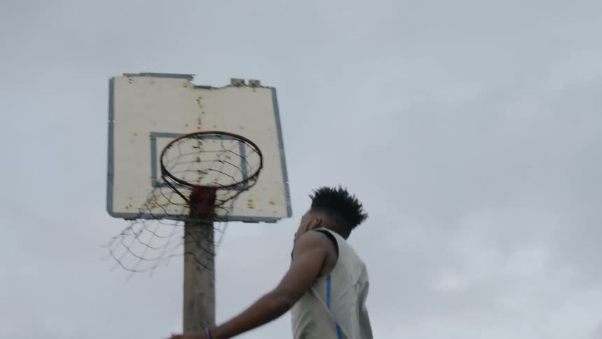 A man dribbling towards a basketball hoop before jumping to perform a layup