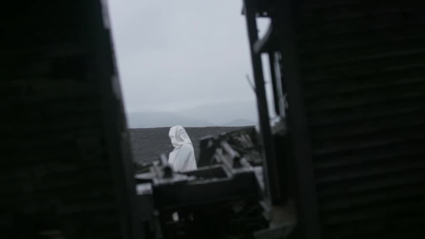 A person wearing white robes is standing outside on a cloudy day