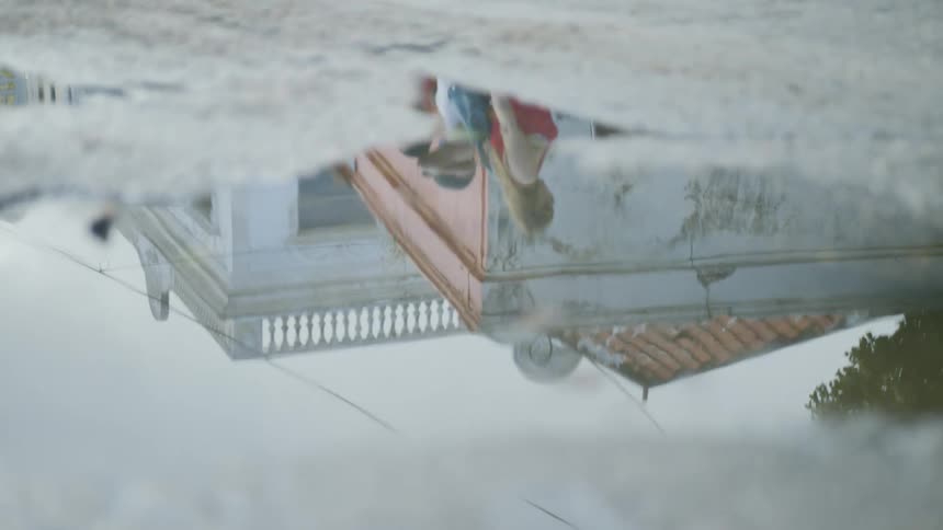 The reflection in a puddle of three people walking