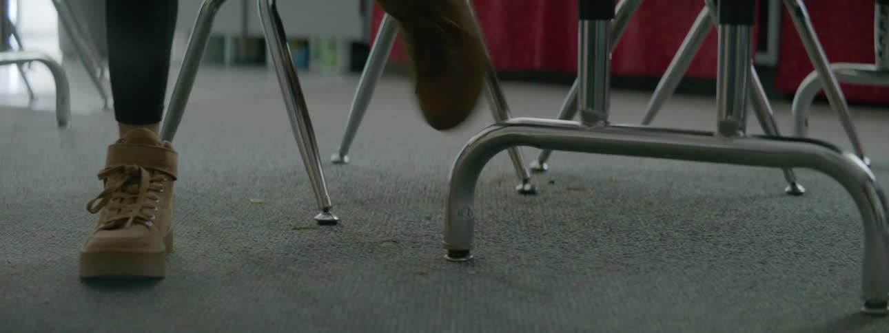 Feet of person standing up from a chair and walking away