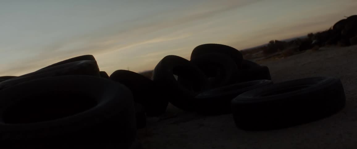 A pile of tires in a desert in the evening