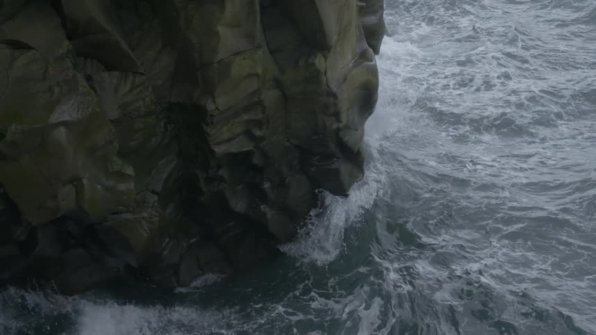 Waves crash against a large rock formation