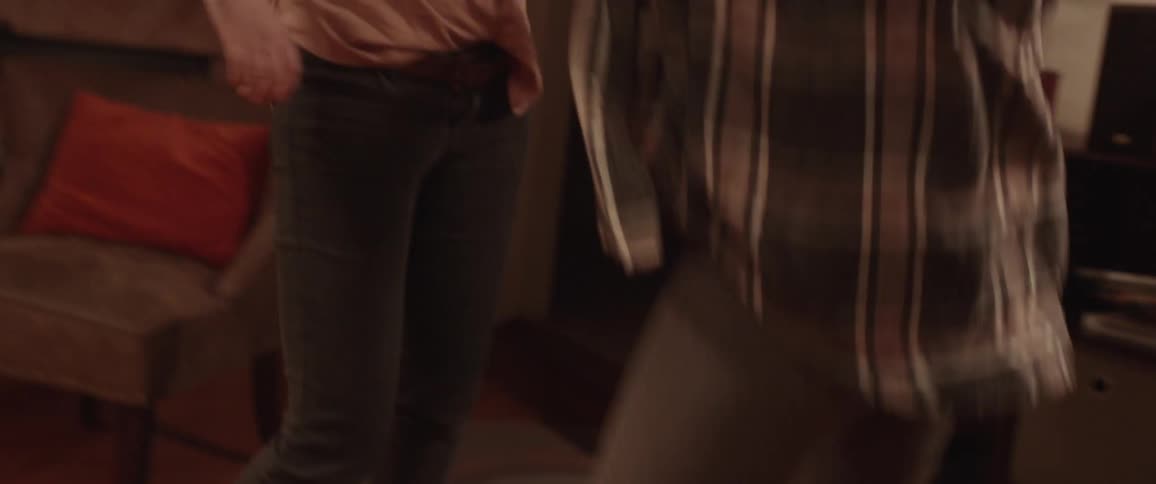 Two white women dance on a rug in a living room