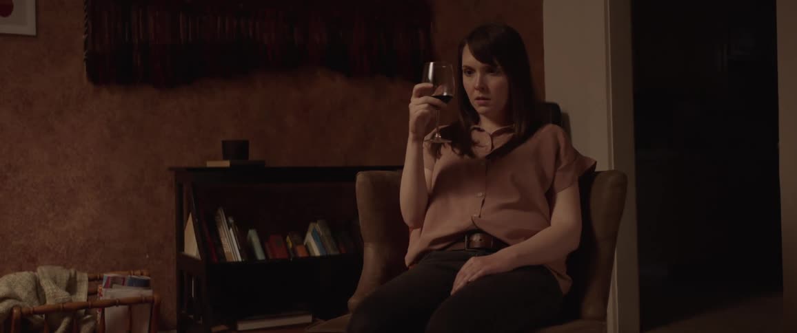 Sad woman sitting in a chair drinks a glass of wine